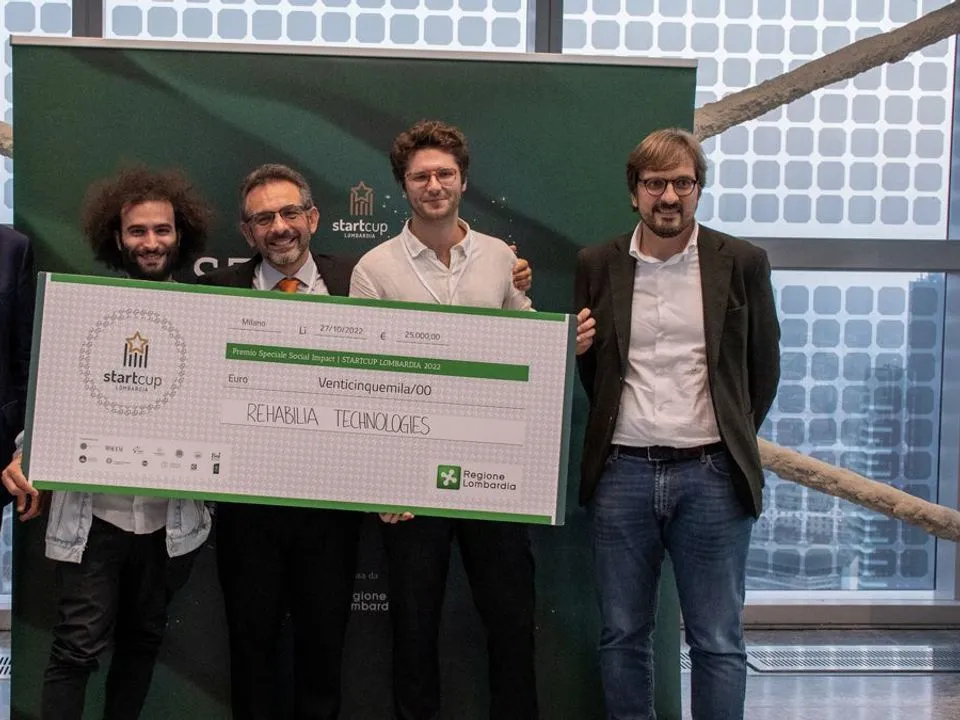 The team holds the Start Cup Lombardia prize cheque on stage.