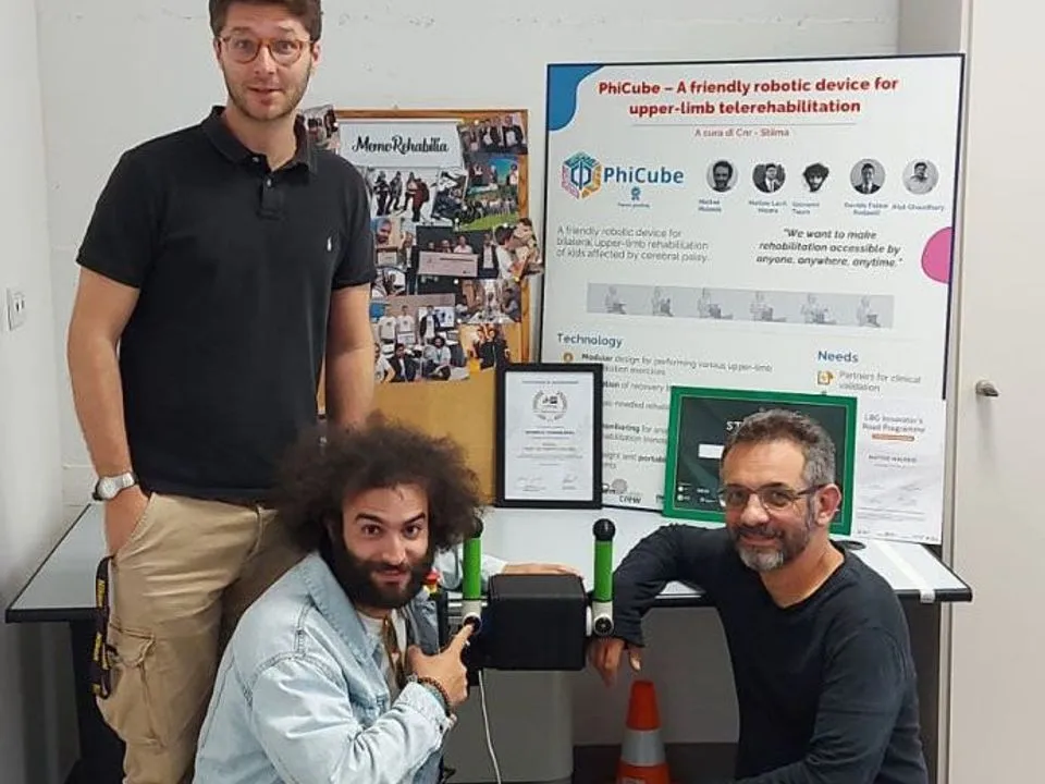 Two founders crouch beside a PhiCube prototype at the lab.