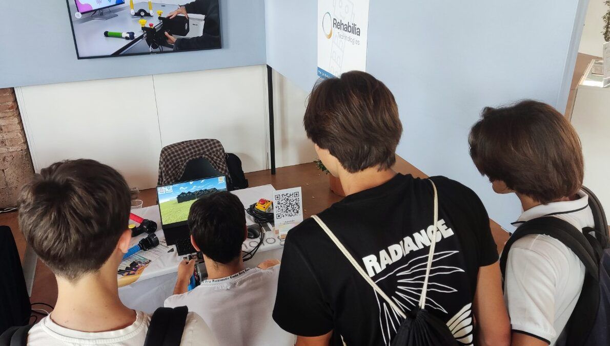 Un groupe de jeunes regarde un jeu de rééducation en 3D sur un ordinateur portable, sur le stand du festival.