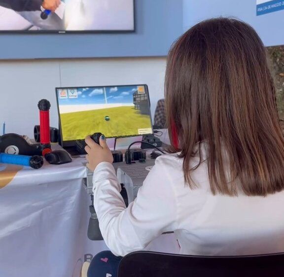 Une fillette utilise PhiCube pour guider une balle dans un décor herbeux en 3D, à l’écran.