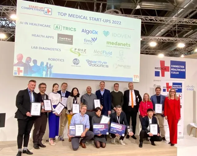 Finalists of the Top Medical Start-ups 2022 competition pose on stage at MEDICA with their award certificates.