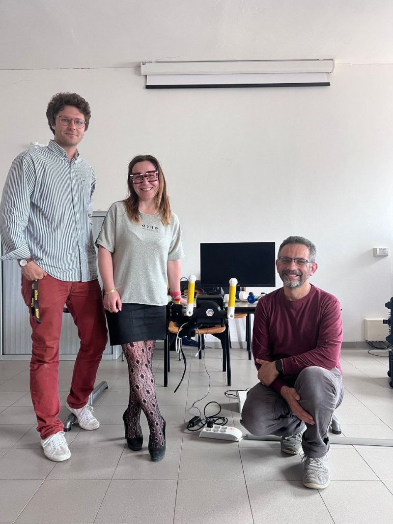 Three people stand beside the PhiCube device during a demo session at IRCCS Fondazione Stella Maris.