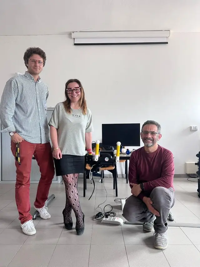 Three people stand beside the PhiCube device during a demo session at IRCCS Fondazione Stella Maris.