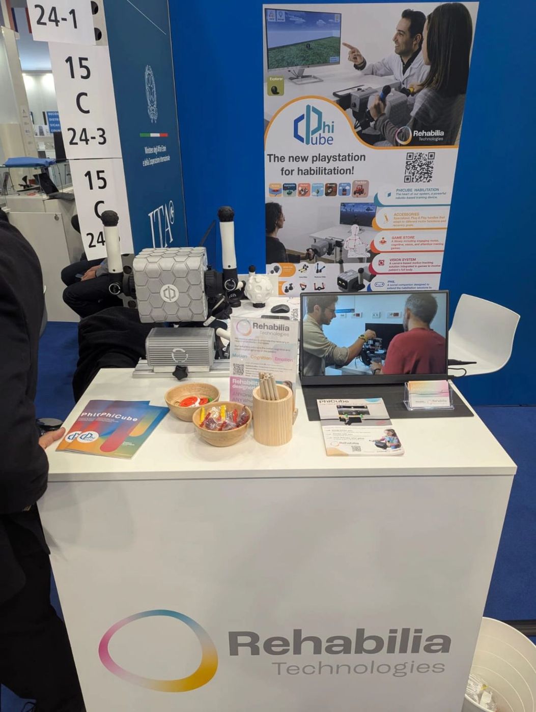 Die Robotereinheit von PhiCube, die Griffe und Informationsmaterial am Stand von Rehabilia Technologies auf der MEDICA 2025.