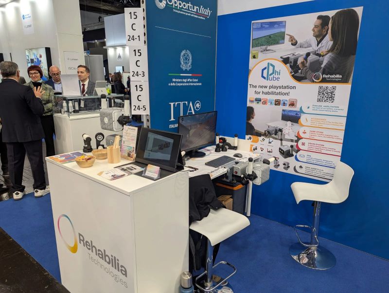 Der Stand von Rehabilia Technologies auf der MEDICA 2025 mit einem Poster zu Zubehör, Game Store und Kamerasystem von PhiCube.