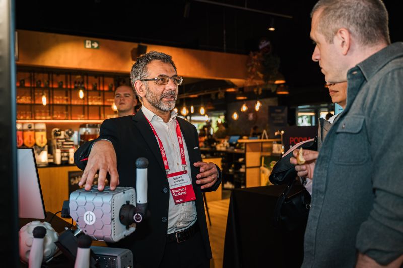 Matteo Malosio habla de PhiCube con un visitante en el estand de Rehabilia en PODIM 2026.
