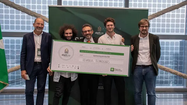 Rehabilia Technologies team members hold a giant cheque for twenty-five thousand euros at the StartCup Lombardia 2022 award ceremony.